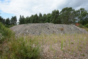 På marken framför högen med massor som inte är kontrollerade ligger järnvägsmakadam. Foto: Berit Önell