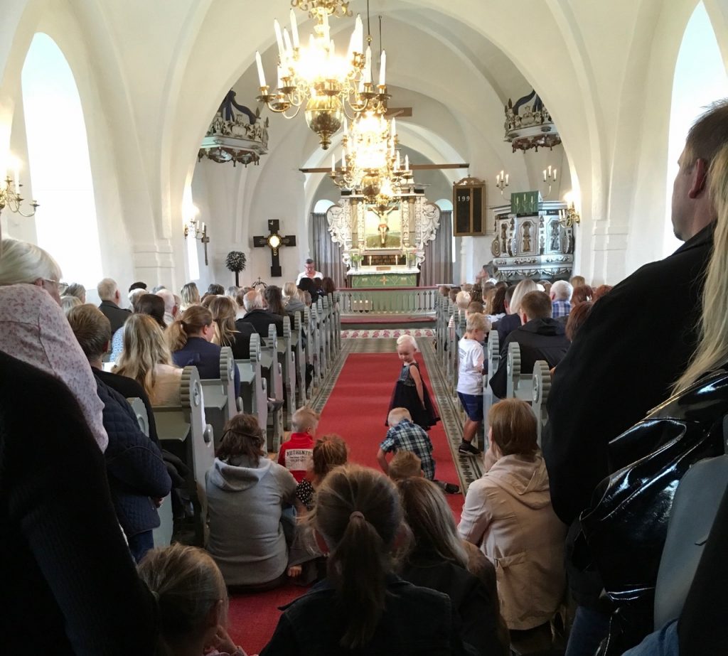 Det var helt fullsatt i Västra Torups lilla vackra kyrka. Drygt 160 personer får rum. Platsbristen är ett litet orosmoment, men än har man till allas glädje inte behövt vidta åtgärder för att begränsa deltagarantal för anhöriga. Connie Asterman, i talarstolen, hälsar alla välkomna.