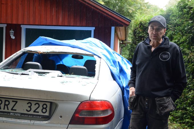 Bilden visar Lars Grewin och den sönderslagna bilen.