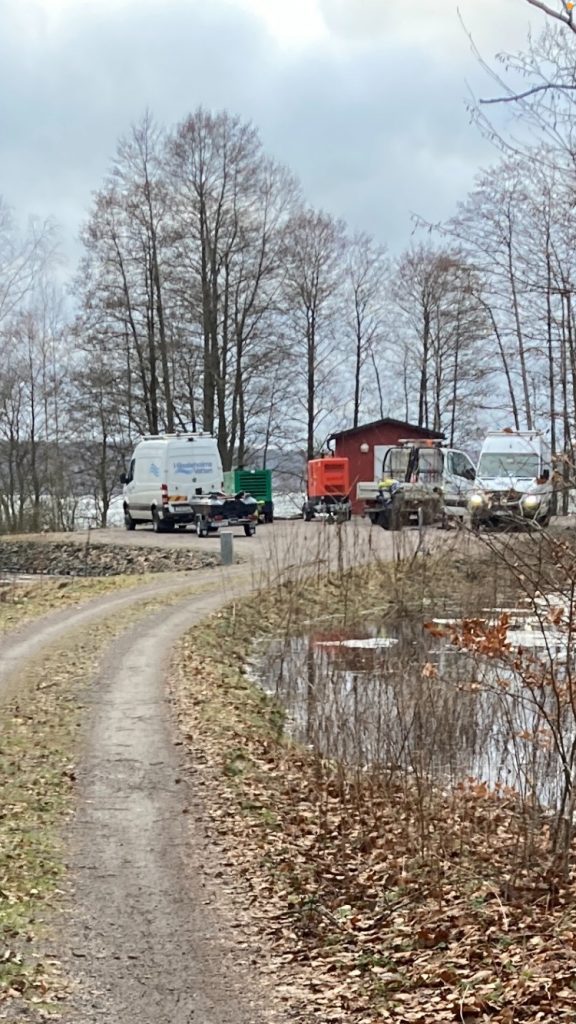 Bilden visar bilar, varav en med båt på släp, vid en pumpstation.