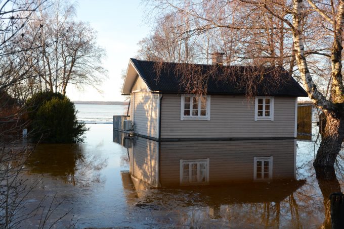 Bilden visar ett hus där vattnet nästan når upp till en värmepump.