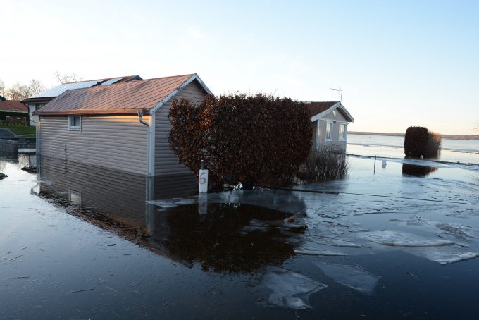 Bilden visar ett hus omringat av vatten med isflak.
