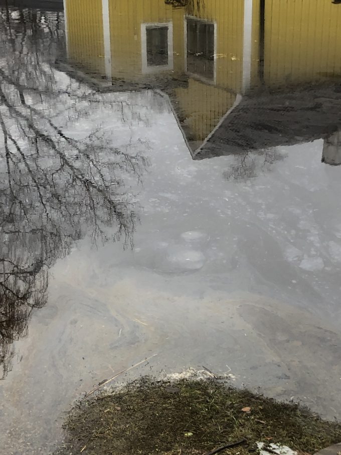 Bilden visar förorenat vatten vid ett översvämmat hus.